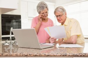 33941183 - senior couple paying their bills with laptop at home in the kitchen